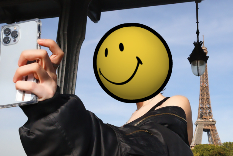 a person wearing all black with a smiley head taking photo on the eiffel tower background